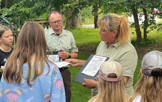Die Ranger Kerstin Titho (rechts im Bild) und Paul Neumann vom Biosphärenreservatsamt Schaalsee-Elbe zeigen den Teilnehmenden des KinderFerienSpaß-Biosphäre die blühende Vielfalt auf Wiesen